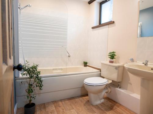 a bathroom with a toilet and a tub and a sink at Barn House Mews in Darlington