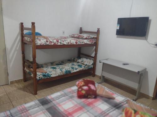 a bedroom with two bunk beds and a tv at Kitnet completa in Guaratinguetá