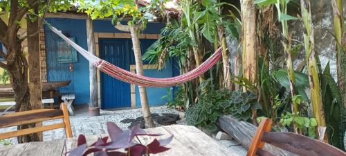 a hammock in front of a house with trees at Casinhas Vila Bonita Azul in Baía Formosa