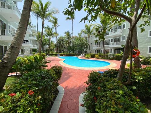 uma piscina de resort com palmeiras e edifícios em Ducassi Sol Caribe Beach em Punta Cana