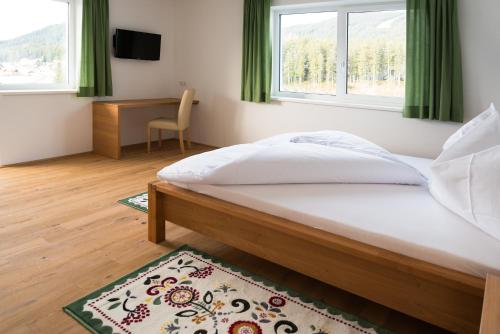 1 dormitorio con cama, escritorio y ventana en Ramsau Appartements Pickl, en Ramsau am Dachstein