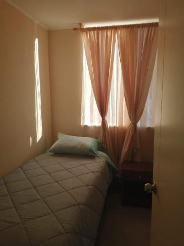 Dormitorio pequeño con cama y ventana en Departamento de 3 habitaciones frente a la universidad de Talca, en Talca