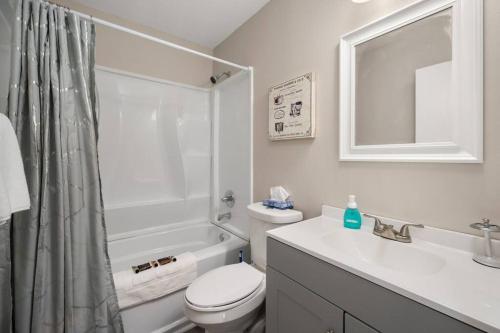 Baño blanco con aseo y lavamanos en HEIRS LIVING : BEAUX - Near Cabrini Hospital . Colleges . 3TVs . Free Parking . Pet Friendly . 2BR Fully Furnished, en Pineville