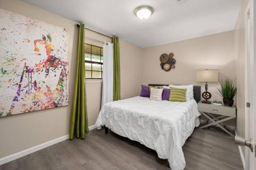 1 dormitorio con 1 cama y una pintura en la pared en HEIRS LIVING : BEAUX - Near Cabrini Hospital . Colleges . 3TVs . Free Parking . Pet Friendly . 2BR Fully Furnished, en Pineville