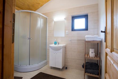 a white bathroom with a shower and a sink at Cabana Dopca in Racoşu de Jos