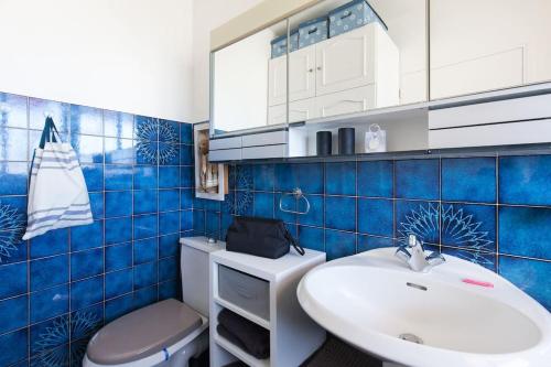 La salle de bains est pourvue de carrelage bleu, d'un lavabo et de toilettes. dans l'établissement Studio vue mer panoramique sur la baie de Cannes, au Cannet
