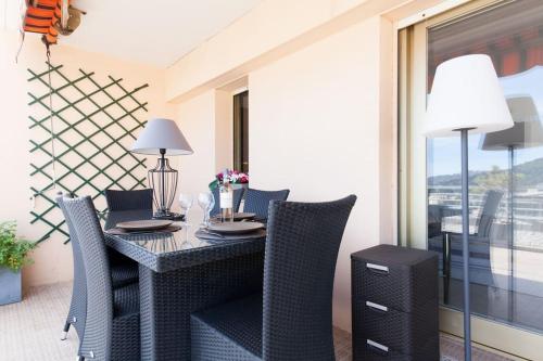 una sala da pranzo con tavolo, sedie e finestra di Studio vue mer panoramique sur la baie de Cannes a Le Cannet