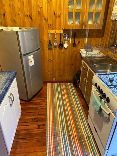 a kitchen with a refrigerator and a stove at Cabañas Campestres Villarrica in Villarrica