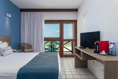 um quarto de hotel com uma cama e uma televisão em Hotel Areias Belas em Maragogi