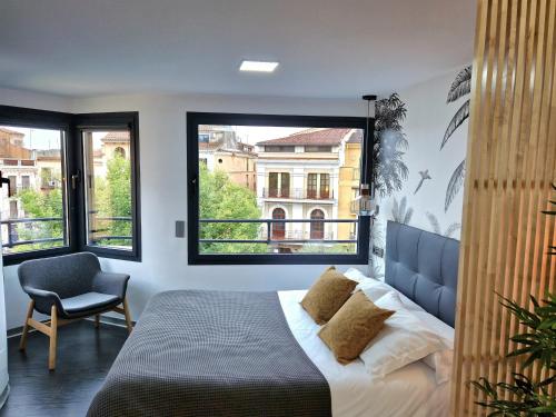 1 dormitorio con 1 cama, 1 silla y 1 ventana en Plasencia Plaza Mayor Luxury, en Plasencia
