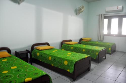 a room with three beds with green and yellow at Garden Hotel e Eventos in Benevides