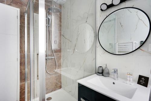 La salle de bains est pourvue d'une douche, d'un lavabo et d'un miroir. dans l'établissement CMG Solidarite 5, à Montreuil