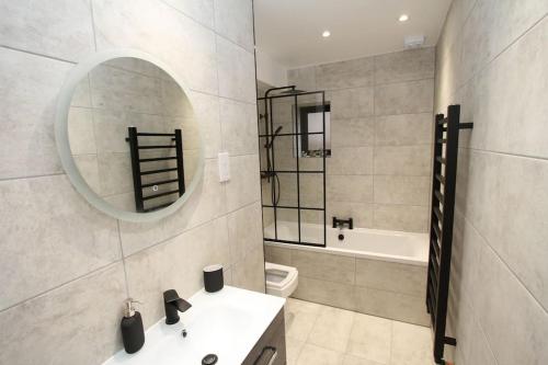 a bathroom with a sink and a mirror and a tub at Lovely One Bed Apartment-Near All Transport-Village-FreeParking in London