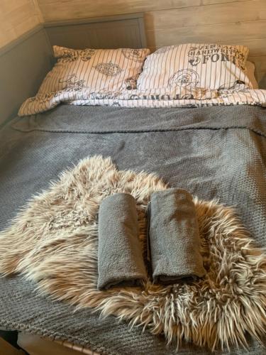 een bed met twee kussens en een harig tapijt erop bij Off mode - Erdei faház a tóparton in Komló