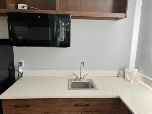 a kitchen counter with a sink and a microwave at HomeTowne Studios by Red Roof Georgetown, KY in Georgetown