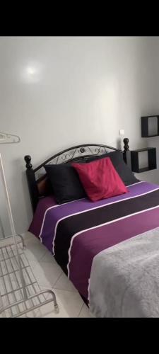 una camera da letto con letto con lenzuola viola e cuscini rossi di KHAWARIZMI 5 ad Agadir