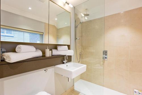 bagno con lavandino, doccia e specchio di 2 Bed Mews House Marylebone a Londra