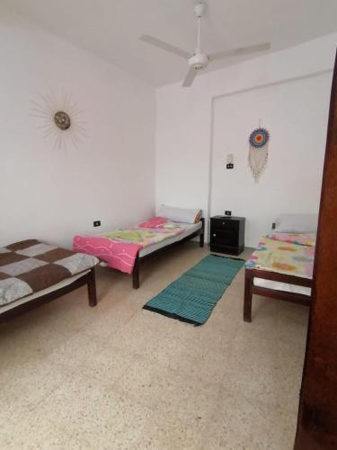 a room with three beds and mats on the floor at Rose Guest House in Luxor