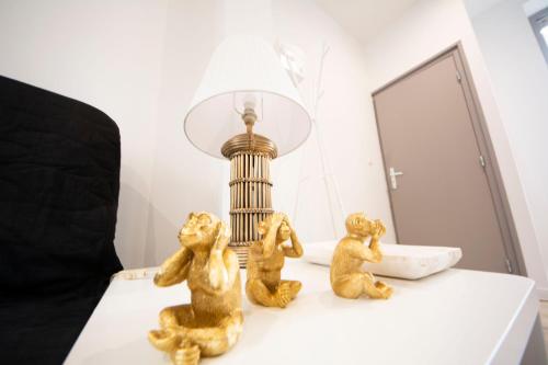 tre piccole statuette sedute su un tavolo accanto a una lampada di IVOIRIA !!! SUBLIME Studio HOME STAGING AU CENTRE VILLE !!! a Saint-Quentin