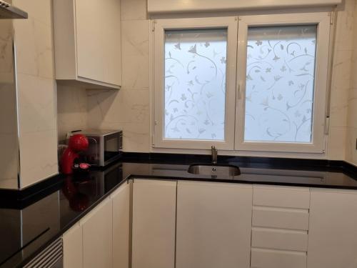 uma cozinha com uma janela, um lavatório e um micro-ondas em 136A Apartamento moderno en Playa San Lorenzo em Gijón