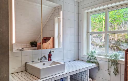 a white bathroom with a sink and a window at 4 Bedroom Nice Home In Farsund in Farsund