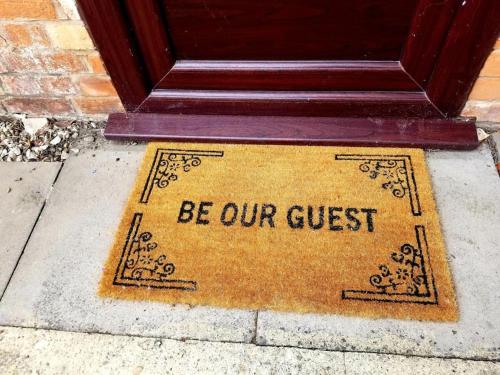a door mat with the words be our guest at The Lodge at Pickford House NEC and B'Ham Airport, Coventry in Coventry