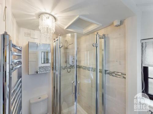 a bathroom with a shower and a toilet and a chandelier at The Lodge at Pickford House NEC and B'Ham Airport, Coventry in Coventry