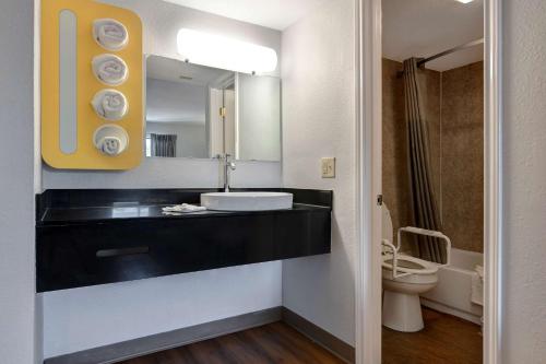 ein Badezimmer mit einem Waschbecken, einem Spiegel und einem WC in der Unterkunft Motel 6-Sulphur Springs, TX in Sulphur Springs