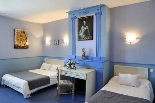 um quarto azul com 2 camas e uma secretária com uma cadeira em Logis Hostellerie Du Cheval Blanc em Sainte-Maure-de-Touraine