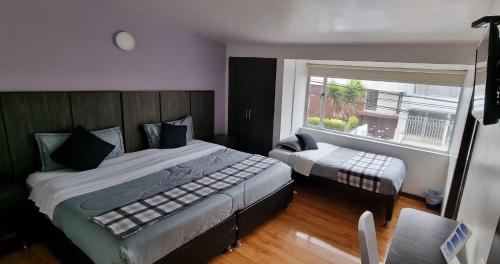 a bedroom with a large bed and a window at Stay Blue Hotel in Bogotá