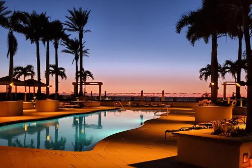 a pool with palm trees and a sunset in the background at Sandpearl Residences 606 in Clearwater Beach