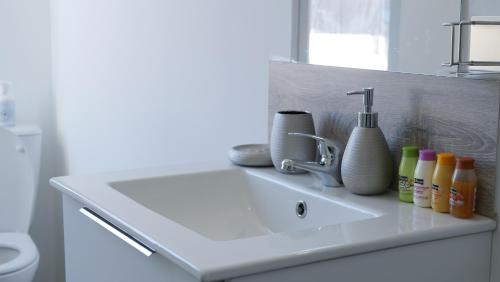 un lavandino con bottiglie e un rubinetto in bagno di IVOIRIA !!! SUBLIME Studio HOME STAGING AU CENTRE VILLE !!! a Saint-Quentin