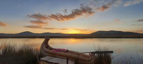 a boat on a lake with the sunset in the background at Uros Lodge Perú in Puno