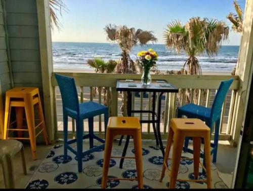 a table and chairs on a porch with a view of the ocean at Oceanfront at The Dawns in Galveston