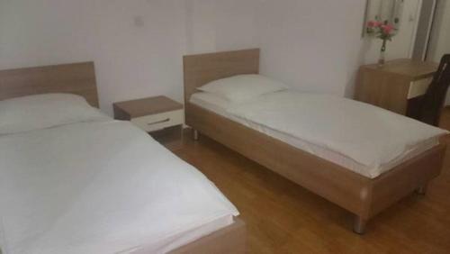 two twin beds in a room with two tables at Lugarnica in Zagreb