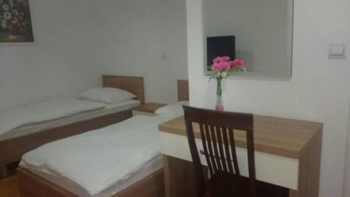 a room with two beds and a table with a vase of flowers at Lugarnica in Zagreb