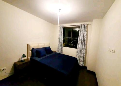 um quarto com uma cama azul e uma janela em Acogedor departamento con 2 dormitorios em Cochabamba