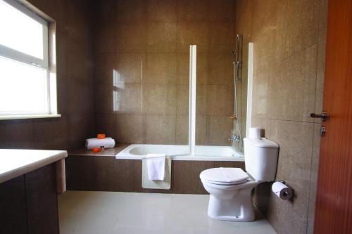een badkamer met een bad, een toilet en een douche bij Montebelo Indy Maputo Congress Hotel in Maputo