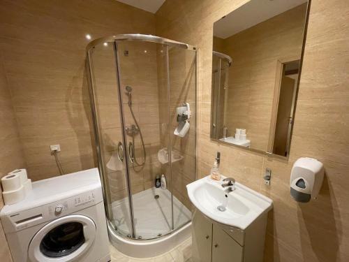 a bathroom with a shower and a sink and a washing machine at Lullaby Private Rooms in Poznań
