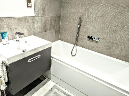 a bathroom with a white tub and a sink at Lovely 3 Bed Home for Colleagues in Darlington