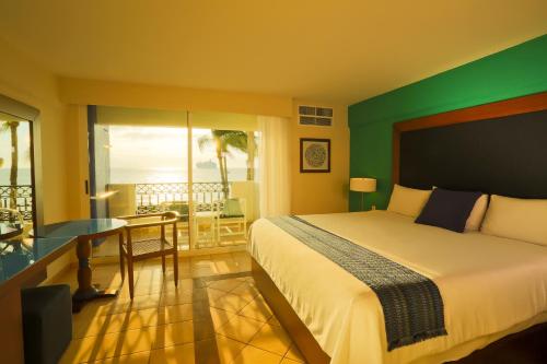 a bedroom with a bed and a balcony with the ocean at Crown Paradise Golden All Inclusive Resort - Adults Only in Puerto Vallarta