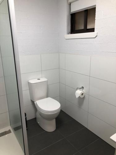 a white bathroom with a toilet and a window at Colonial Inn Guest Rooms in Yackandandah