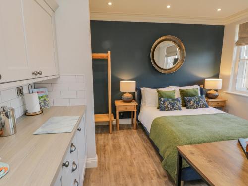 a bedroom with a bed and a kitchen with a mirror at Fenby Suite in Saltburn-by-the-Sea