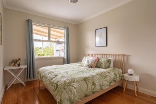 1 dormitorio con cama y ventana en Pebbleton, Retro Riverside Cottage, Tamar Valley, en Gravelly Beach
