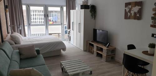 a bedroom with a bed and a couch and a tv at Reformado Apartamento - Centro Alicante in Alicante