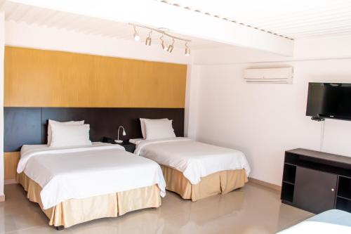a hotel room with two beds and a flat screen tv at HOTEl TANGARA in Pereira