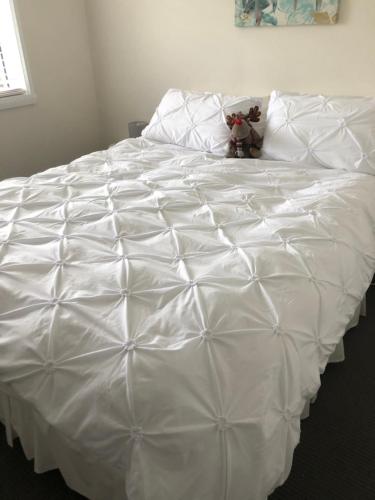 a white bed with a teddy bear sitting on top of it at Cape View B and B in Table Cape