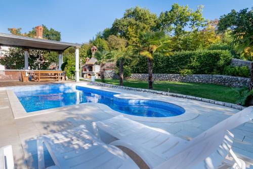 una piscina con due sedie bianche accanto a una casa di Apartments with swimming pool Opatija - Pobri, Opatija - 16390 a Matulji (Mattuglie)