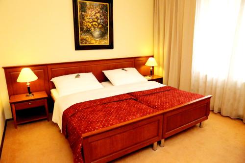 a bedroom with a bed and two lamps and a painting at Hotel Matyšák in Bratislava