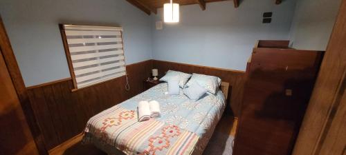 een kleine slaapkamer met een bed met schoenen erop bij Cabañas IBY y KIARA para 4 en Puerto Varas in Puerto Varas